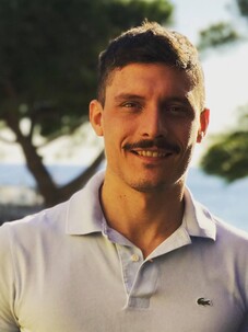 Barbarino Simone mit Schnurrbart und weißem Hemd vor sonniger Naturkulisse.